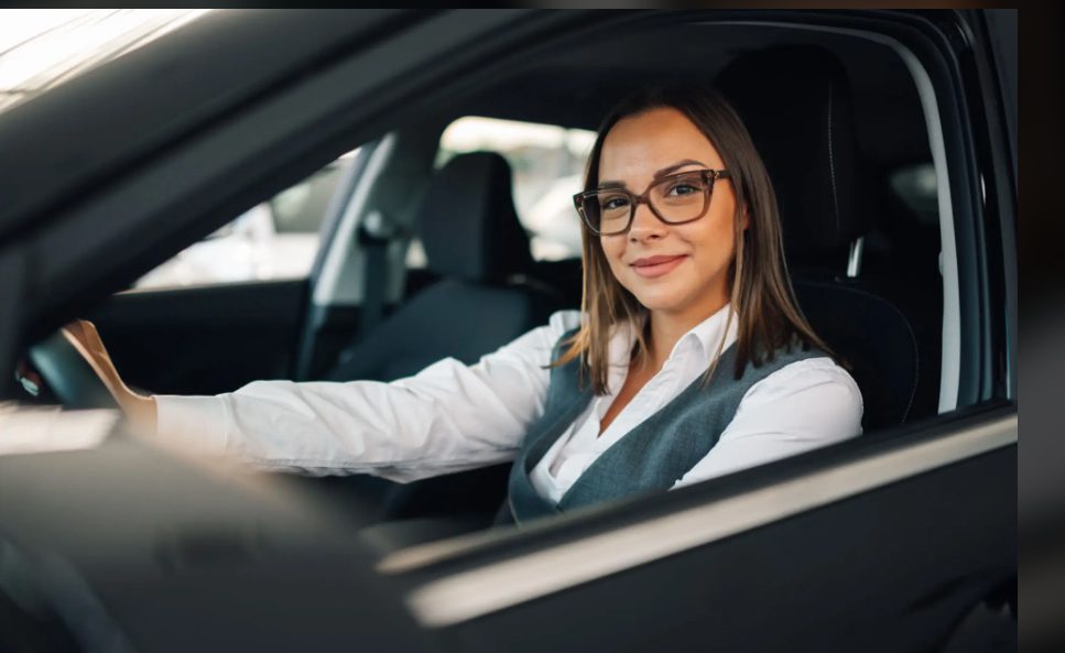 Confident woman sitting in the driver's seat of a car, smiling.